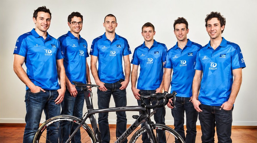 Équipe de six personnes en tenue bleue posant devant un vélo